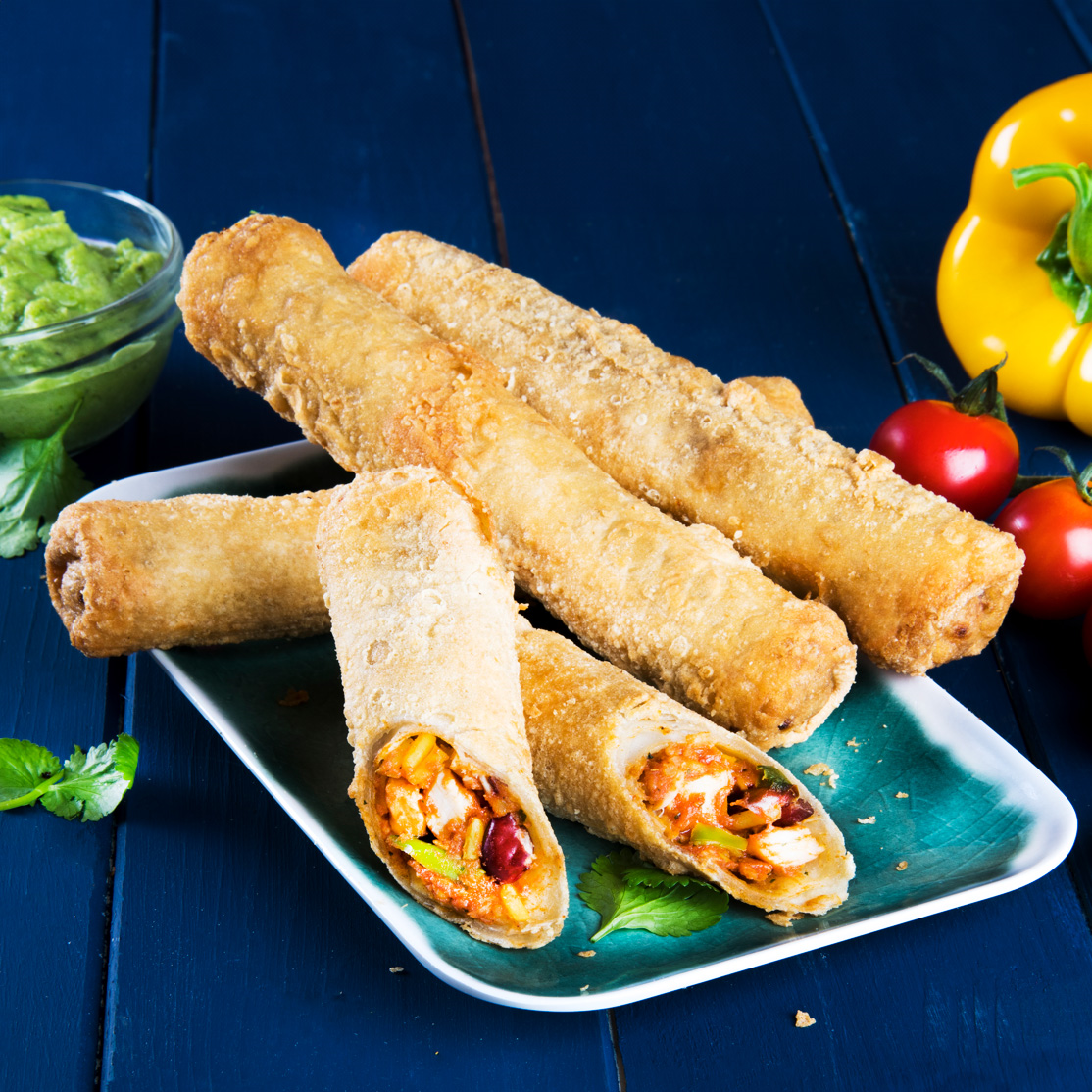 Three plated Taquito's with one cut in half to show a Chicken